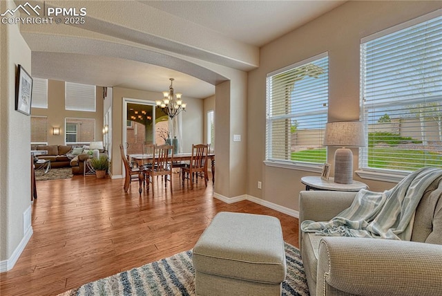 9539 Lizard Rock Trl, Colorado Springs, CO 80924 - living room with an inviting chandelier, arched walkways, baseboards, and wood finished floors