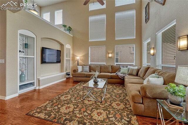 9539 Lizard Rock Trl, Colorado Springs, CO 80924 - living area with a towering ceiling, wood finished floors, baseboards, arched walkways, and a ceiling fan