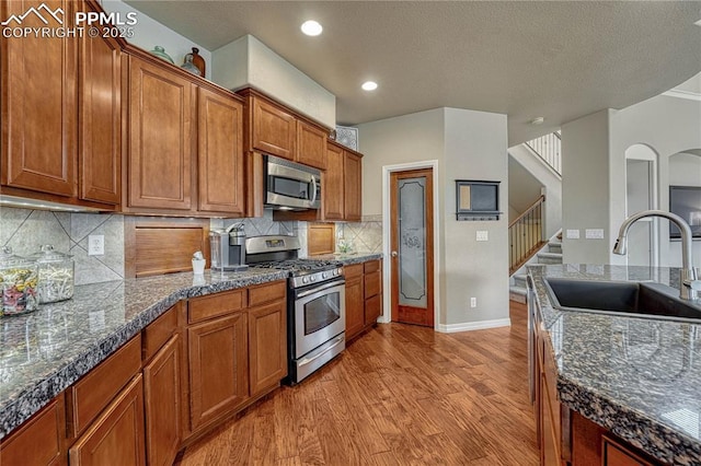 9539 Lizard Rock Trl, Colorado Springs, CO 80924 - kitchen featuring baseboards, brown cabinets, a sink, light wood-style flooring, and stainless steel appliances