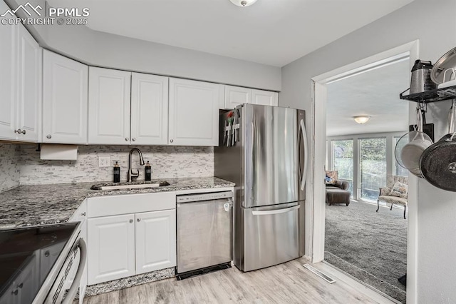 kitchen featuring light wood-type flooring, stainless steel appliances, a sink, and white cabinetry