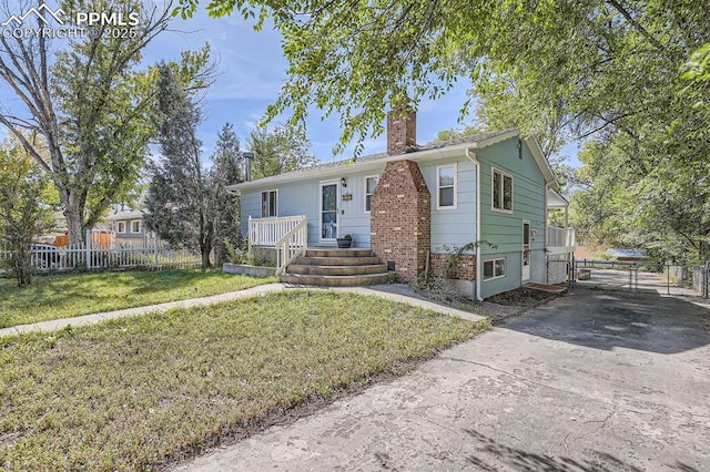 view of front of property featuring a gate, a chimney, a front lawn, concrete driveway, and fence