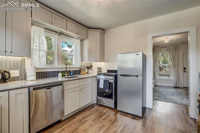 519 W Bijou St, Colorado Springs, CO 80905 - kitchen featuring a sink, appliances with stainless steel finishes, light wood-style floors, light countertops, and backsplash