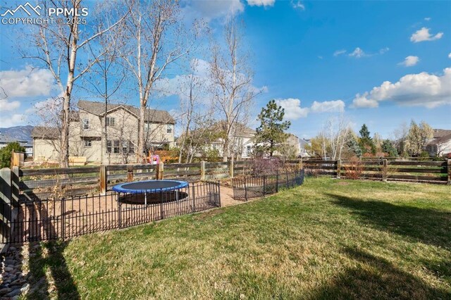 view of yard featuring fence and a trampoline