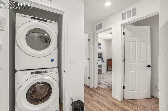 laundry room with laundry area, light wood finished floors, stacked washer and dryer, and visible vents