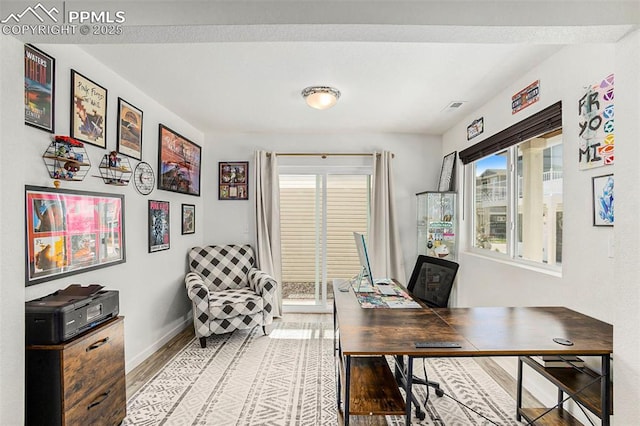 office area with light wood-type flooring, baseboards, and a wealth of natural light
