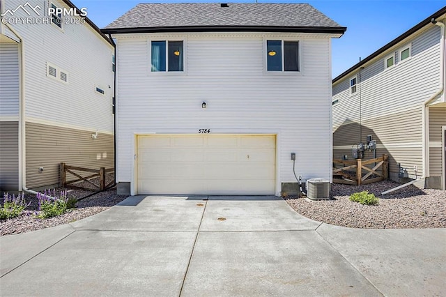 back of house featuring fence, an attached garage, a shingled roof, and concrete driveway