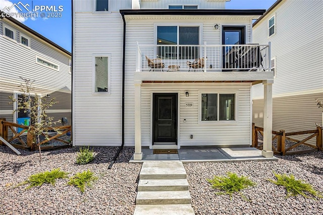 view of front of house with fence, a balcony, and board and batten siding