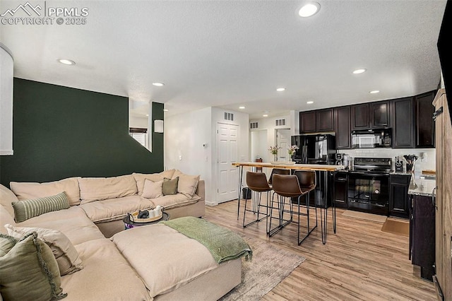 living area featuring light wood-style floors, visible vents, and recessed lighting