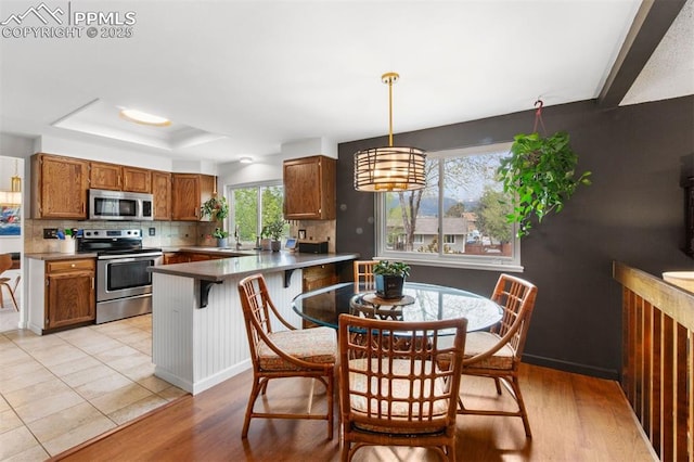 840 Quail Lake Cir, Colorado Springs, CO 80906 - kitchen with hanging light fixtures, appliances with stainless steel finishes, brown cabinets, backsplash, and a peninsula
