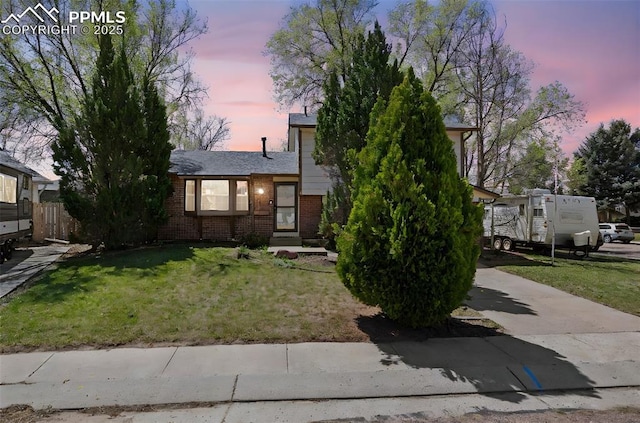 view of front of property with a front lawn, brick siding, and fence