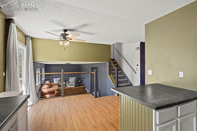 kitchen featuring light wood finished floors, dark countertops, a textured ceiling, and ceiling fan