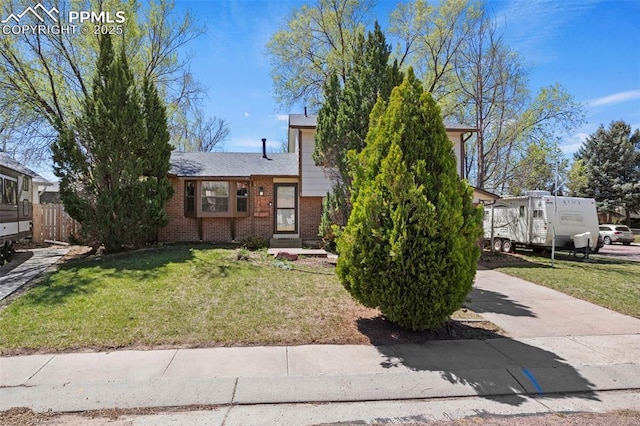 view of front of home featuring fence, a front lawn, and brick siding
