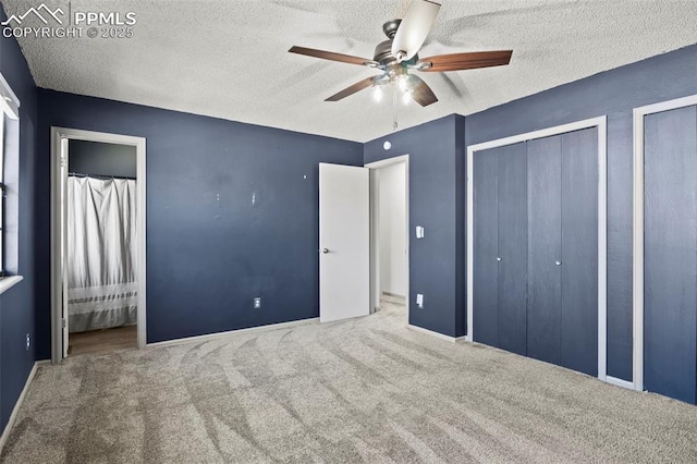 unfurnished bedroom with multiple closets, carpet floors, a textured ceiling, and baseboards