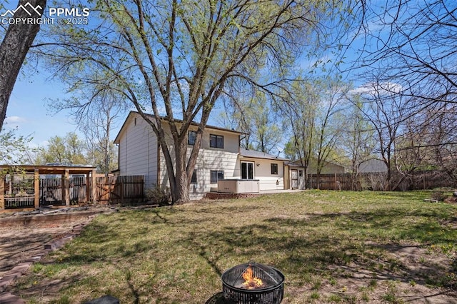 rear view of house with a fire pit, fence, and a yard