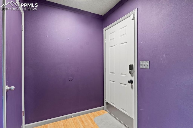 doorway with baseboards, wood finished floors, and a textured ceiling