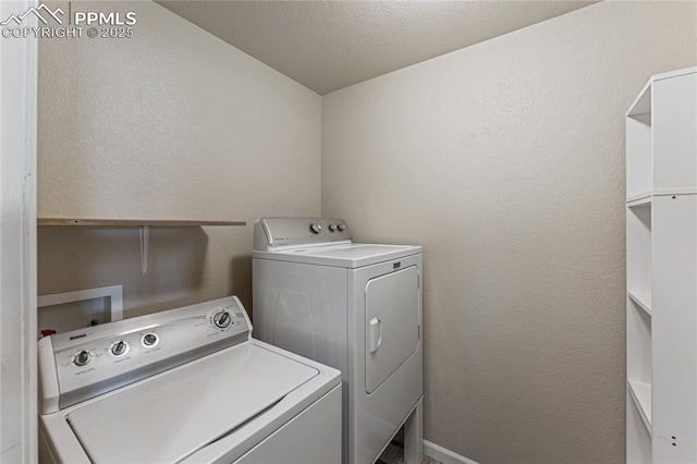 laundry room with baseboards, a textured wall, laundry area, and washer and clothes dryer