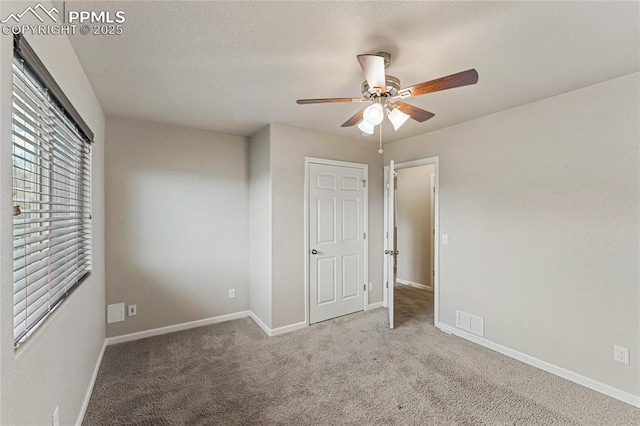 unfurnished bedroom with baseboards, ceiling fan, carpet, and visible vents