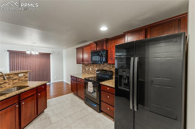 kitchen with tasteful backsplash, a sink, light stone counters, black appliances, and an inviting chandelier