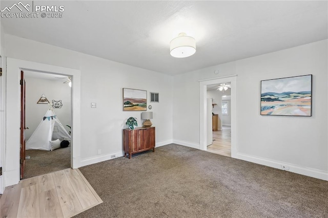 carpeted spare room featuring a ceiling fan and baseboards