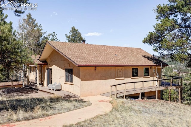 280 Highland Meadows Dr, Florissant, CO 80816 - rear view of house with stucco siding, roof with shingles, and a deck