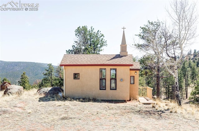 280 Highland Meadows Dr, Florissant, CO 80816 - view of property exterior with a shingled roof, a chimney, and stucco siding