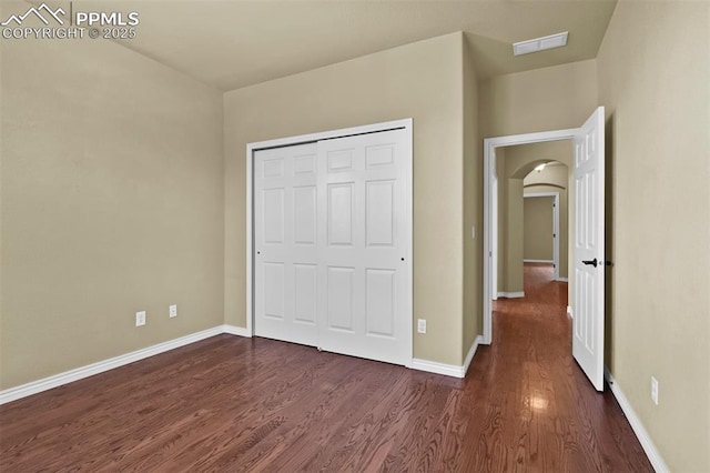 10833 Creede Creek Pt, Colorado Springs, CO 80908 - unfurnished bedroom with dark wood-style flooring, arched walkways, visible vents, and baseboards