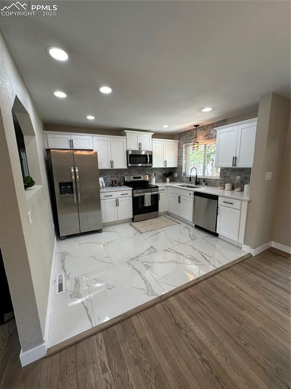 kitchen with a sink, baseboards, stainless steel appliances, recessed lighting, and white cabinetry