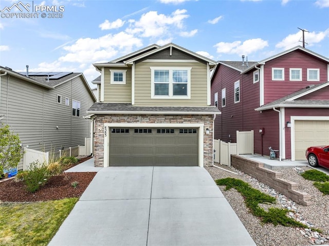 craftsman-style home with an attached garage, fence, driveway, and stone siding
