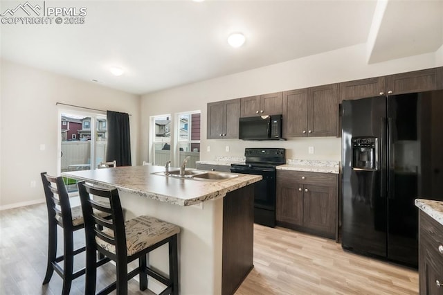 kitchen featuring dark brown cabinets, a sink, black appliances, and light wood-type flooring