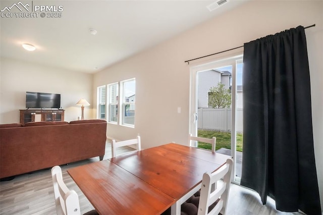 dining area featuring light wood-style floors, a healthy amount of sunlight, and visible vents