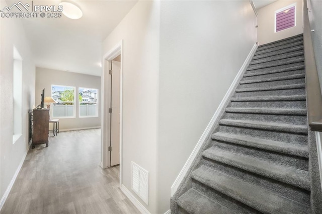 stairs with visible vents, baseboards, and wood finished floors