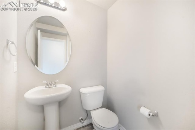 bathroom with a sink, baseboards, and toilet