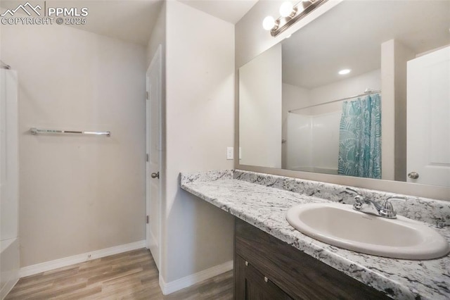 bathroom with a shower with curtain, baseboards, wood finished floors, and vanity