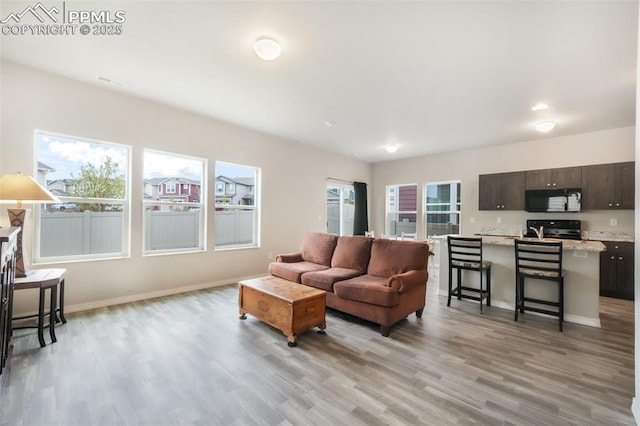 living room with baseboards, visible vents, and light wood finished floors