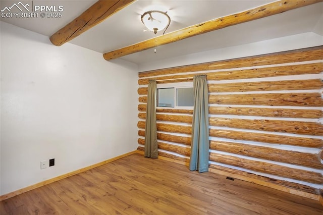 unfurnished room featuring log walls, beam ceiling, baseboards, and wood finished floors