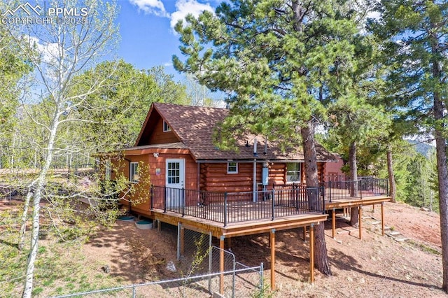 rear view of house with roof with shingles and a wooden deck