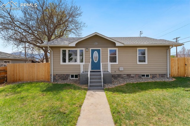bungalow-style home with a shingled roof, a front yard, and fence