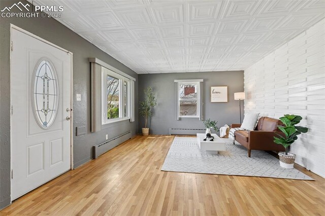foyer entrance featuring a baseboard radiator, an ornate ceiling, and wood finished floors