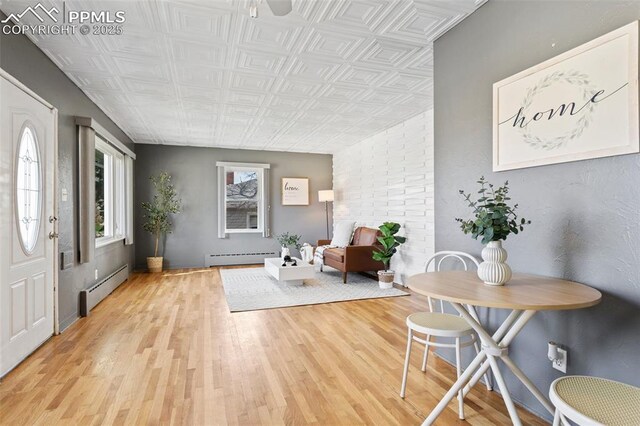 foyer featuring an ornate ceiling, light wood-style floors, and baseboard heating