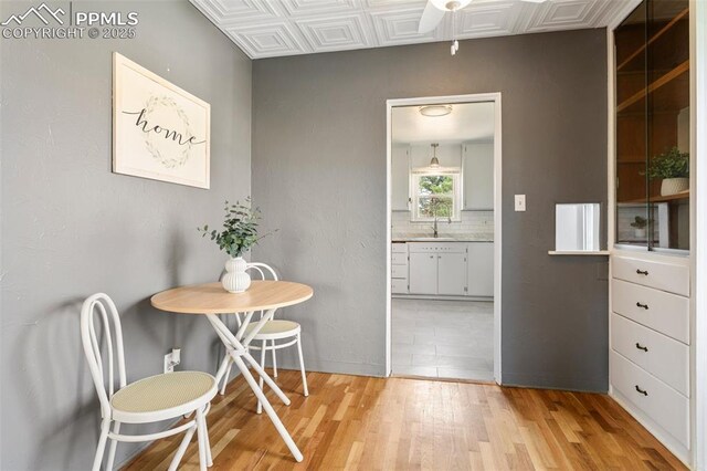 dining area with light wood finished floors, baseboards, and an ornate ceiling