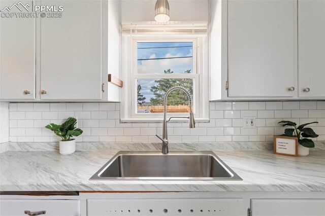 kitchen with white cabinets, backsplash, and a sink