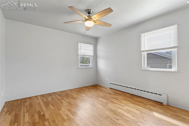 empty room featuring a baseboard heating unit, a ceiling fan, and wood finished floors