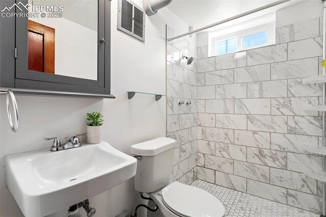 bathroom featuring a shower stall, visible vents, toilet, and a sink
