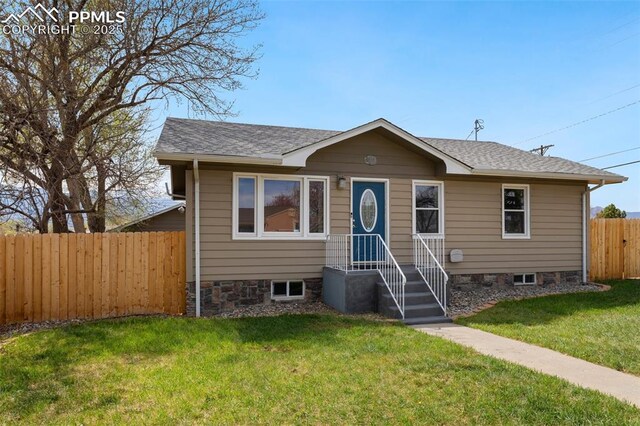 bungalow featuring roof with shingles, a front yard, and fence