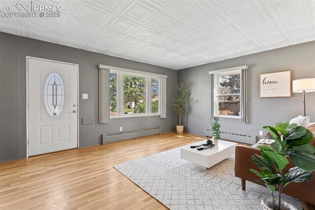 entryway featuring a baseboard heating unit, wood finished floors, and an ornate ceiling