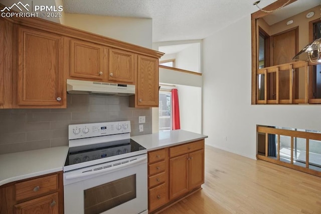 kitchen with tasteful backsplash, white electric stove, brown cabinets, and under cabinet range hood