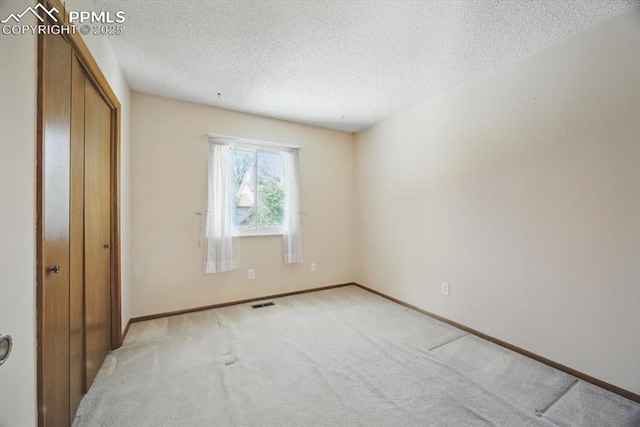 unfurnished bedroom with visible vents, a closet, baseboards, a textured ceiling, and carpet