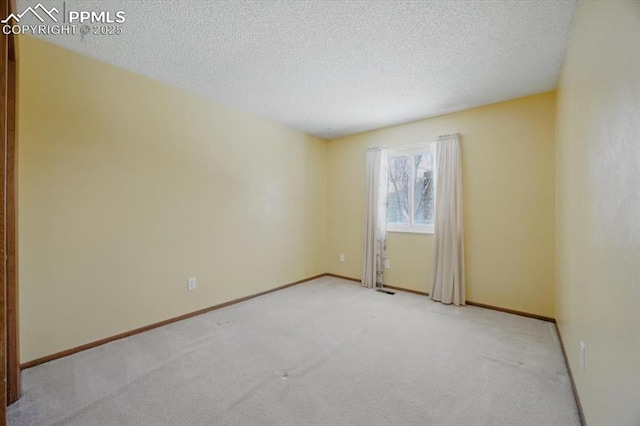 carpeted spare room featuring a textured ceiling and baseboards
