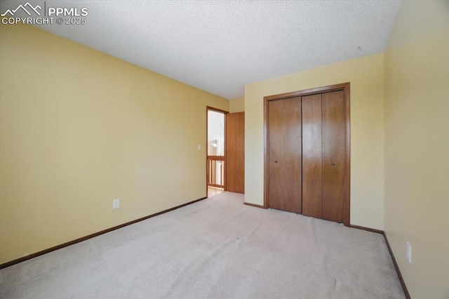 unfurnished bedroom featuring a textured ceiling, baseboards, light colored carpet, and a closet