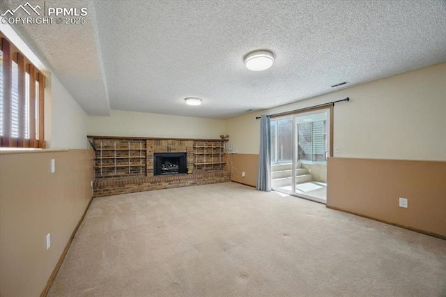 unfurnished living room with a textured ceiling, baseboards, carpet, and a fireplace